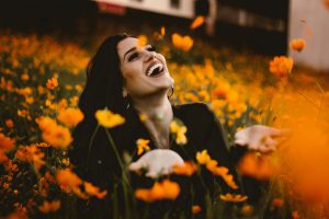 Woman in flower field smiling with joy.